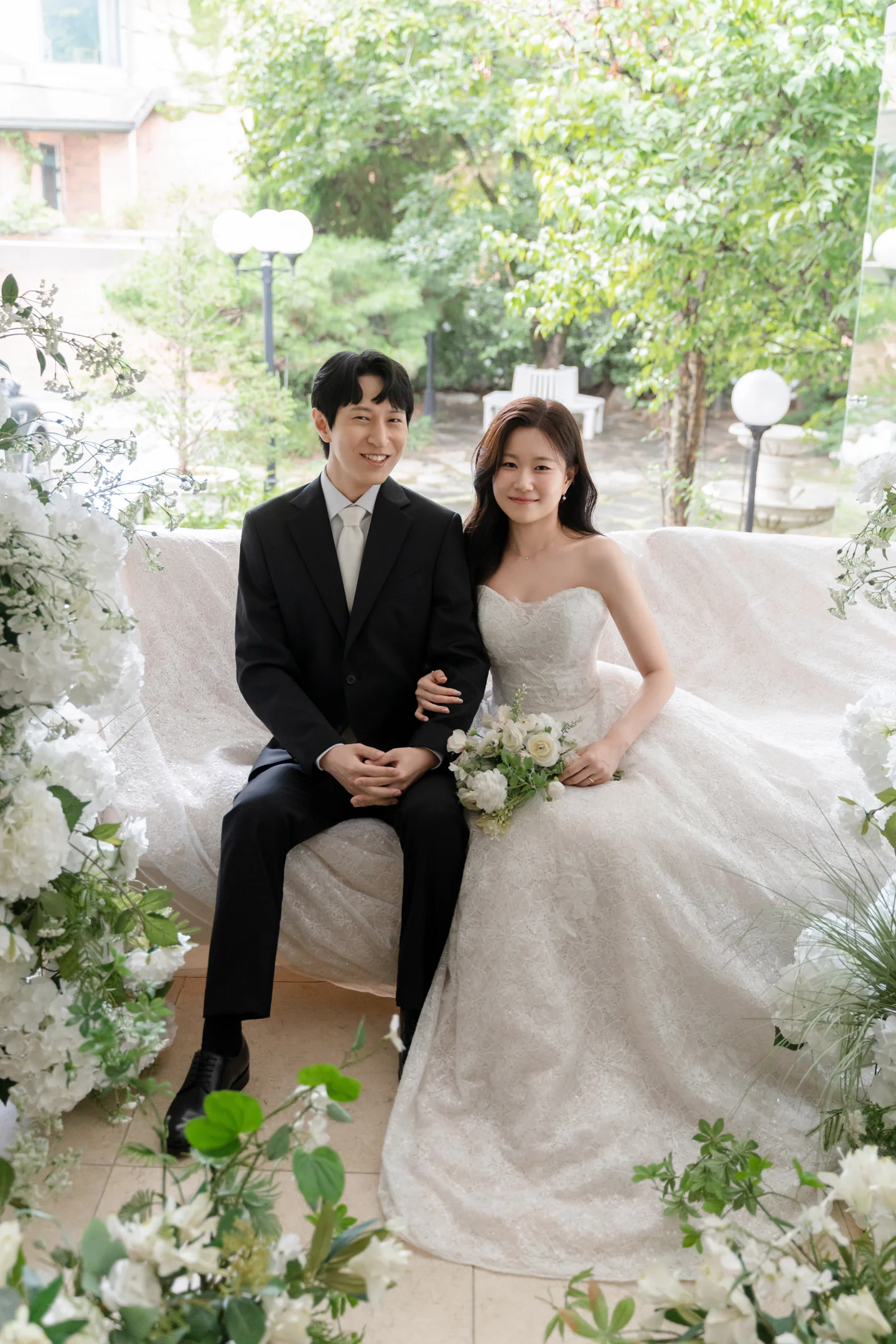 하얀 꽃과 초록 잎 사이에 나란히 앉은 두 사람